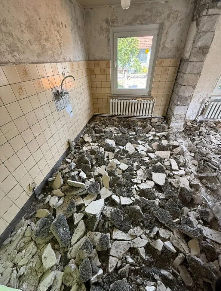 Schutt nach dem Abstemmen vor einer gefliesten Wand